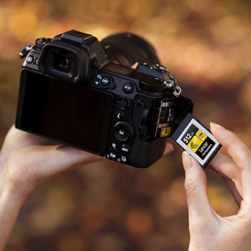 hands holding professional camera, inserting lexar memory card into camera's SD card slot